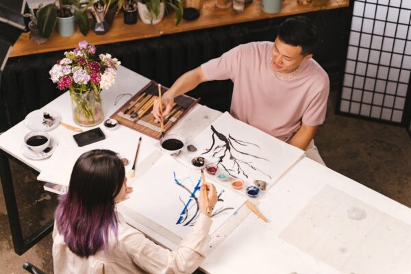 Adults enjoy a creative art workshop, practicing brush painting indoors.